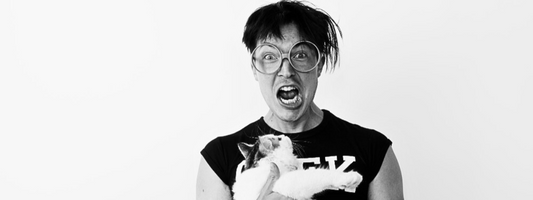 un homme avec de grosses lunettes ronde tiens un chat dans les bras